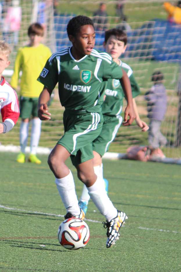 Zwei Fußballspieler in einem Stadion mit einigen Zuschauern und einem Netz im Hintergrund.