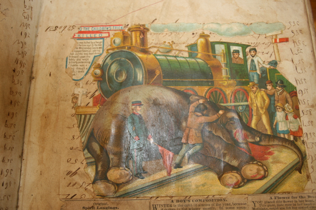 Ein Buch mit Text und einem Bild eines Elefanten, einem Zug auf einer Eisenbahnschiene, einer Gruppe von Menschen und Wolken oben.