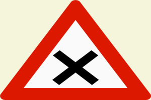 Ein rotes und weißes dreieckiges Verkehrszeichen mit einem schwarzen Kreuz, das eine Warnung vor einer potenziellen Gefahr beim Überqueren der Straße anzeigt.