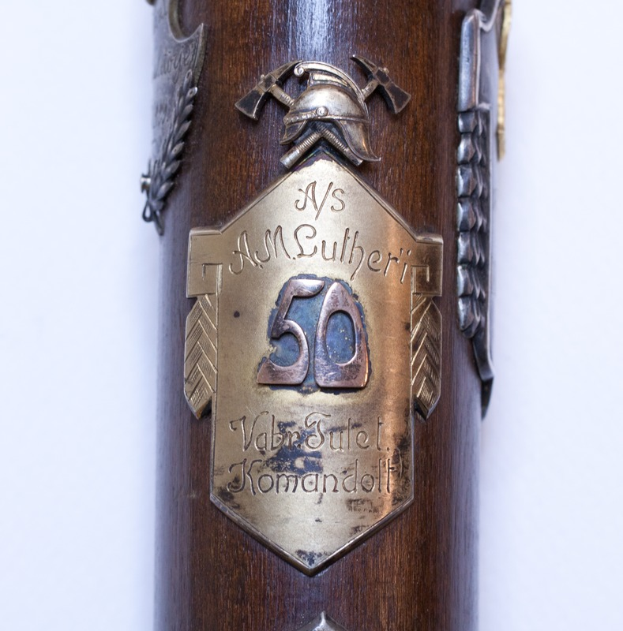 Nahaufnahme eines braunen Gewehrs mit einer Metalltafel, auf der "50. Jahrestag der deutschen Armee" steht.