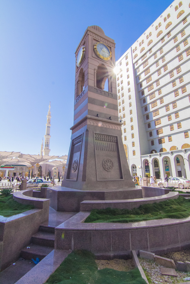 Eine zentrale Struktur mit einer Uhr und einem großen Gebäude auf der rechten Seite.